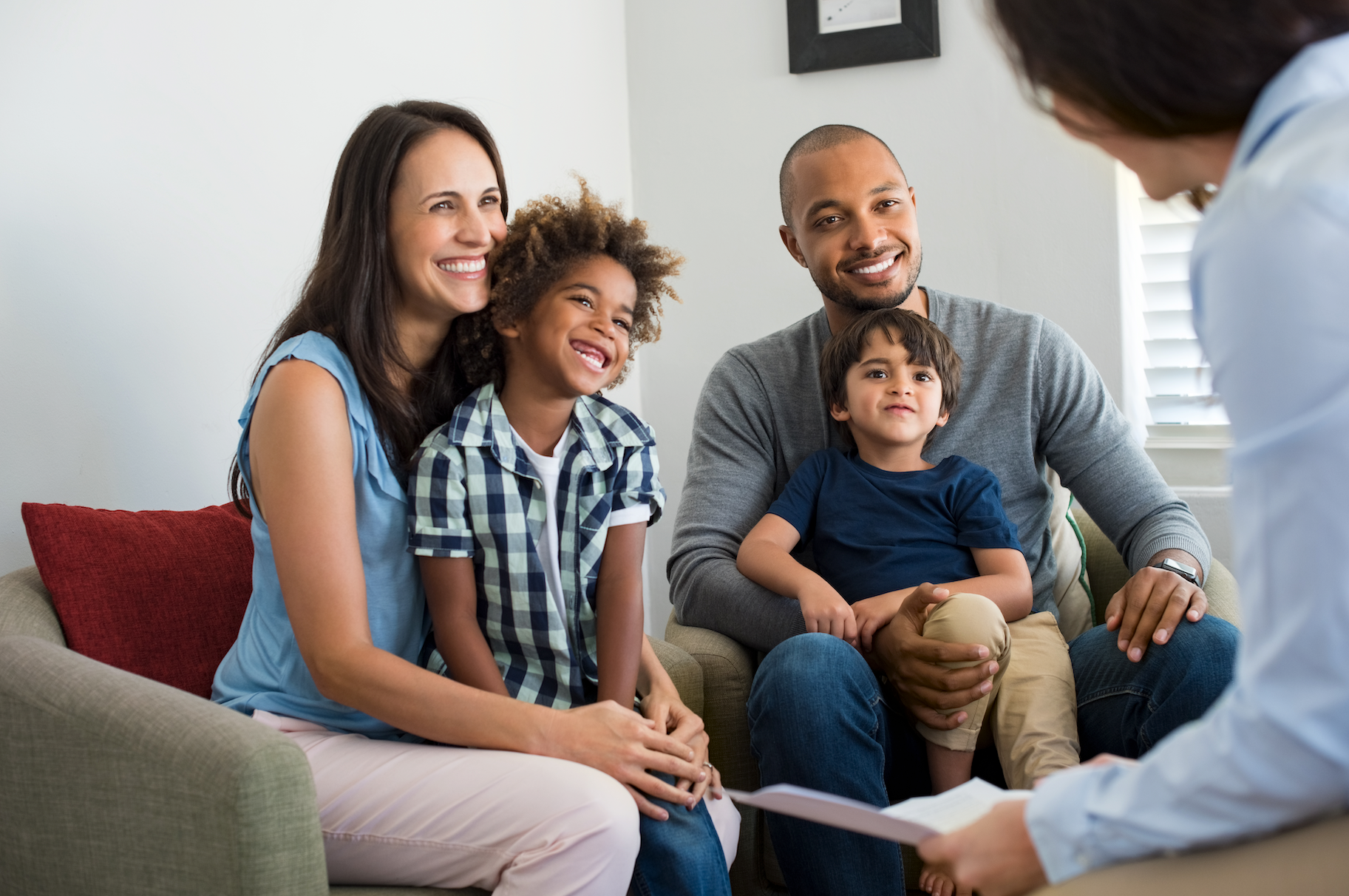 A family is sitting on a couch talking to a doctor.