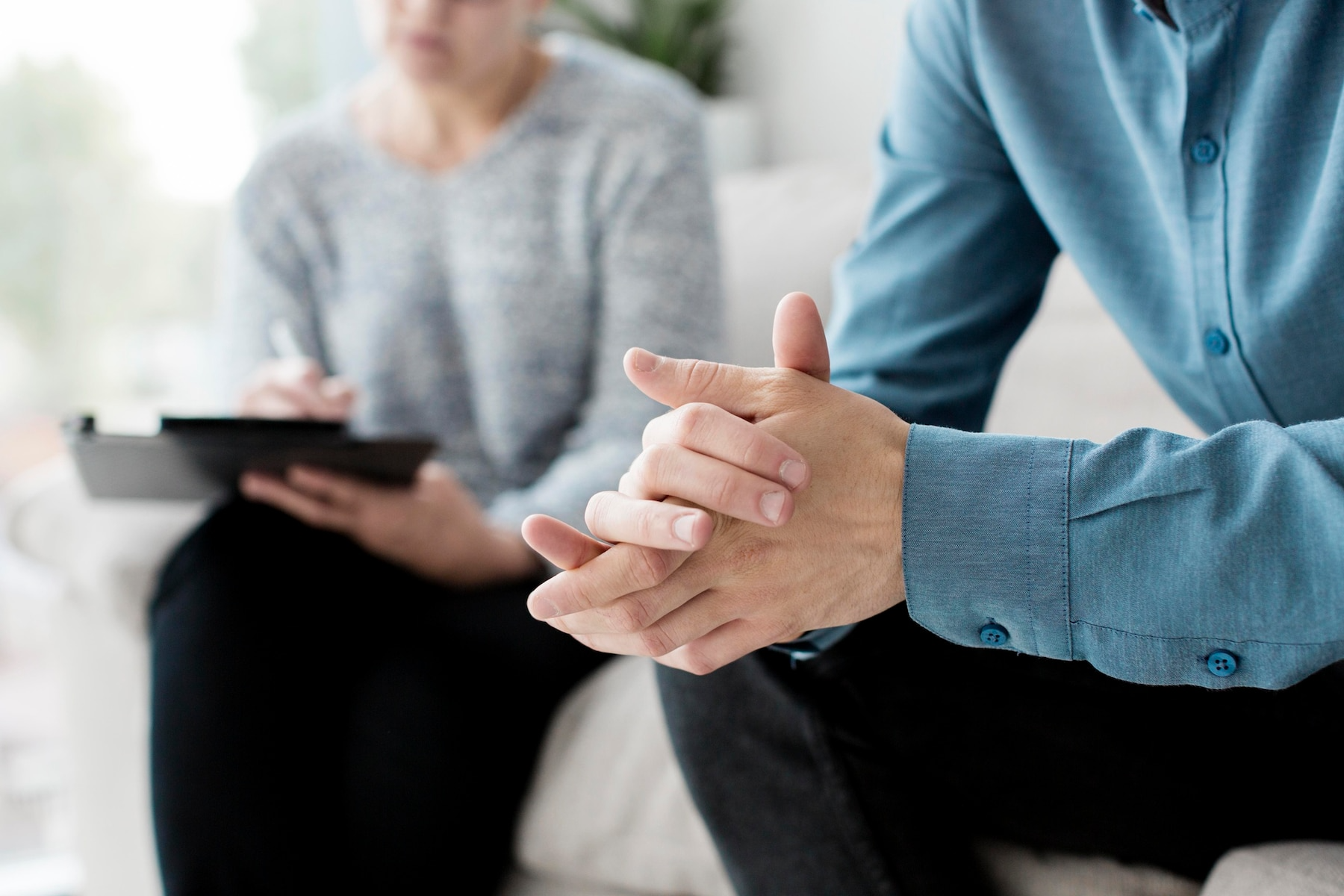 A man and a woman are sitting on a couch talking to each other.