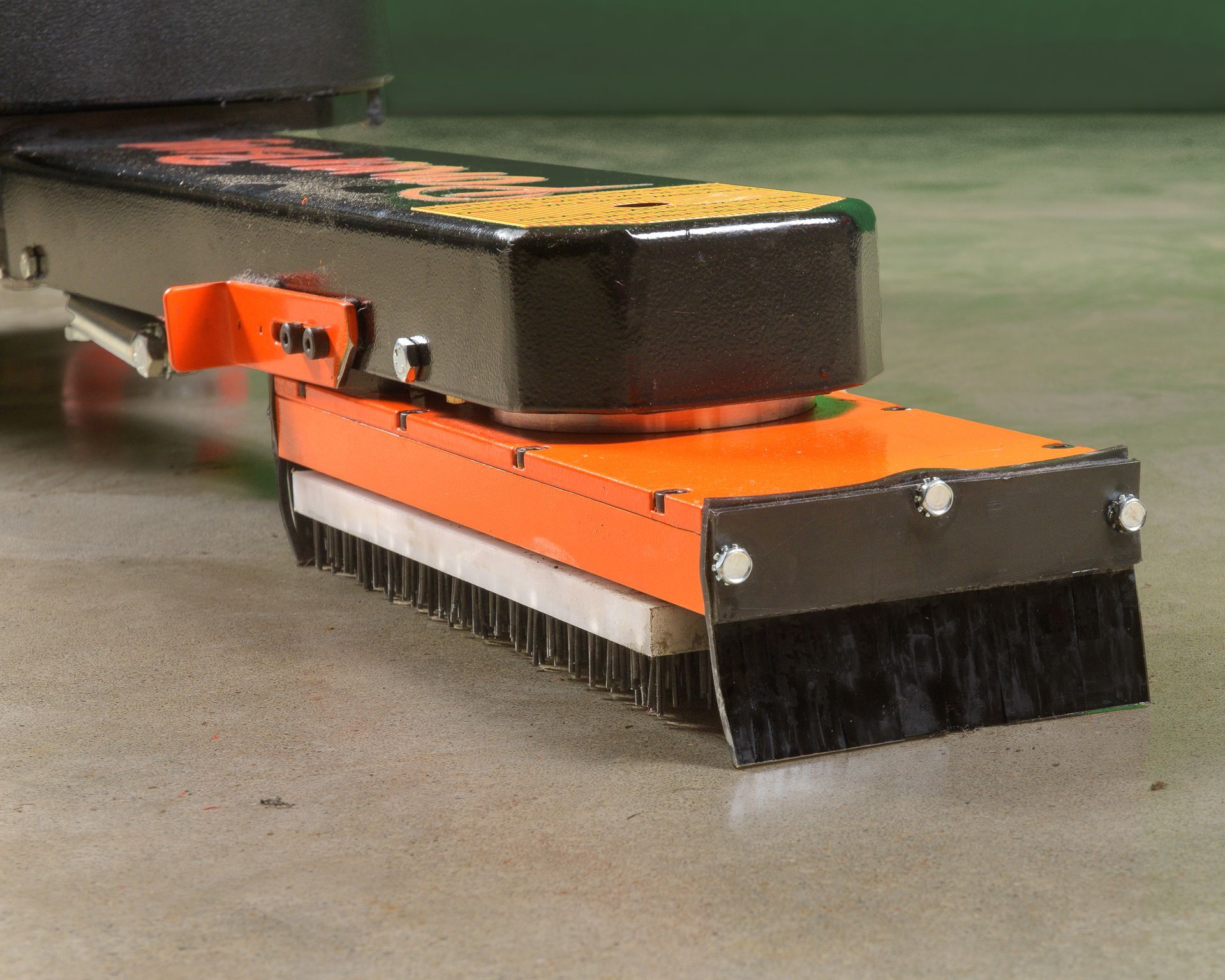 An orange and black machine with a brush attached to it