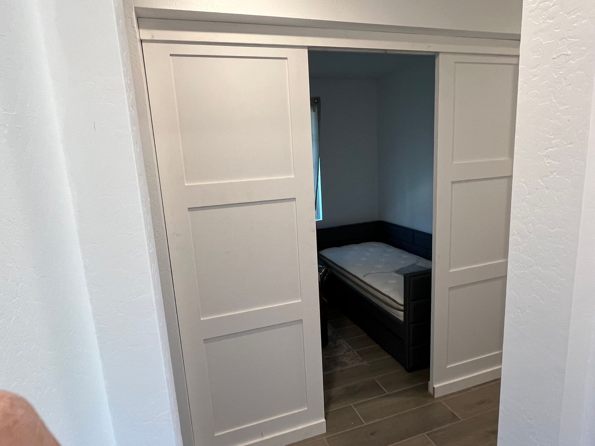 A bedroom with a bed and sliding doors leading to it.