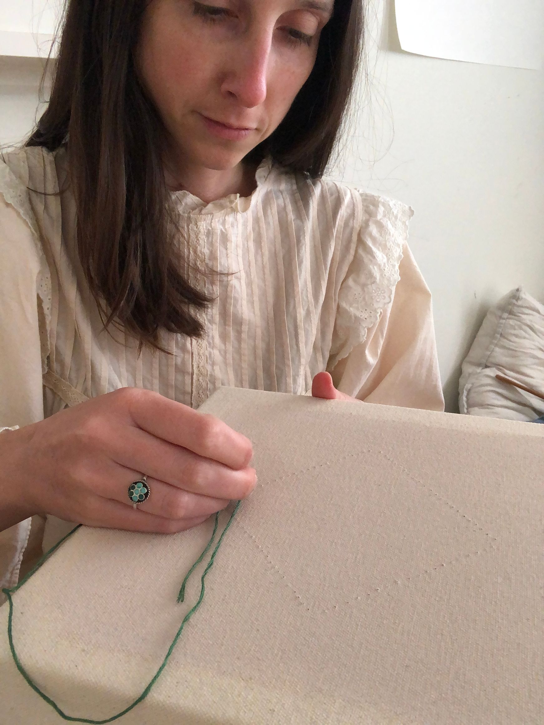 a close up of Emily Keating Snyder in her studio embroidering a diamond shape onto a pre-stretched canvas 