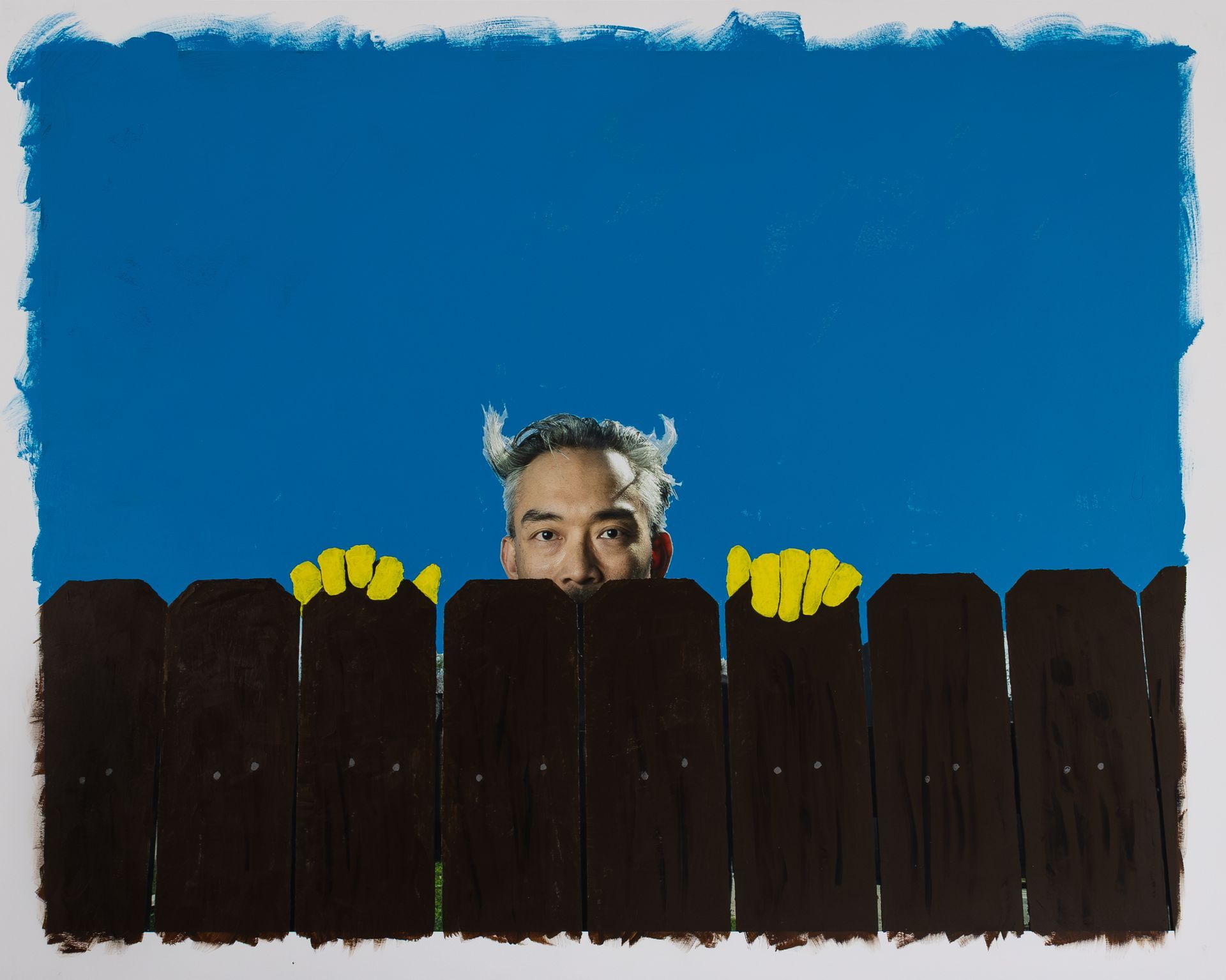 Man peering over a fence wearing yellow gloves and devil horns background solid blue