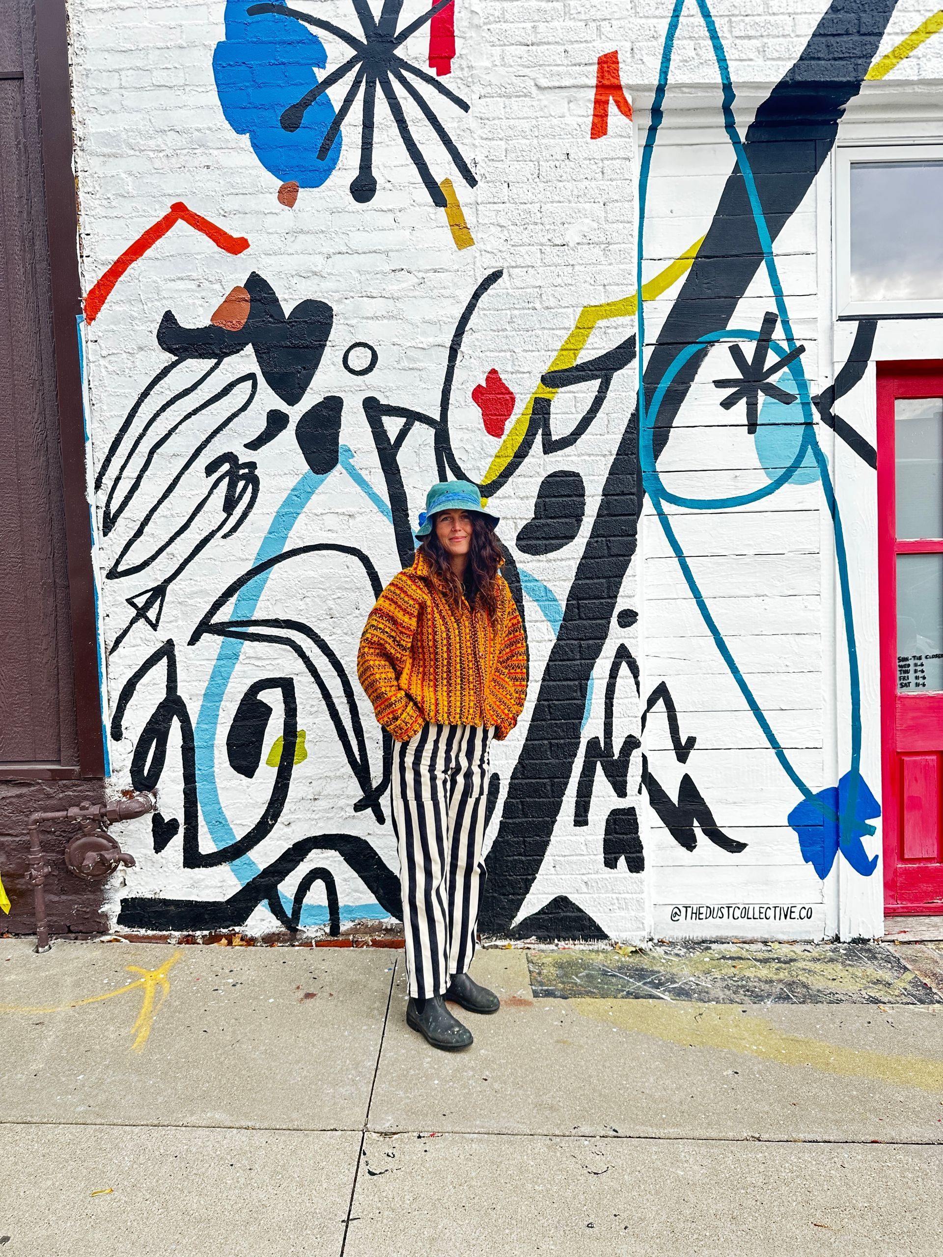 Ashley Mary standing in front of her mural at Dust Collective Co