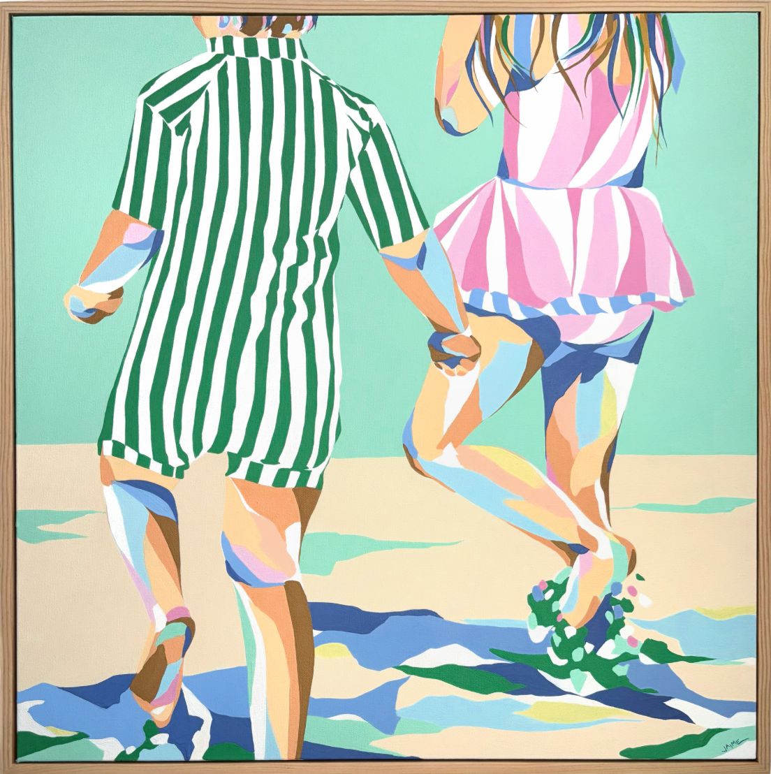 two children skipping through sand and water wearing striped dresses in the sun
