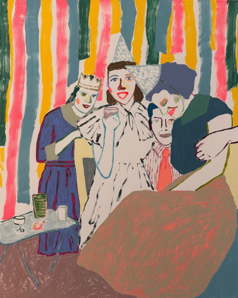 streamers in the background with one woman sitting being hugged by a man and two individuals standing behind them smiling with party hats/crowns on