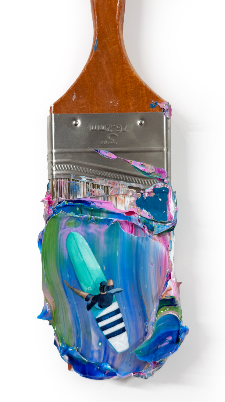 painted paint brush with blue background featuring a man sitting on a mint green surf board in a blue suit