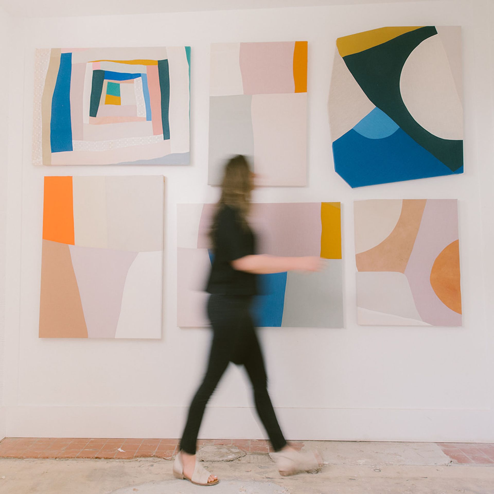 Sydney in her studio, walking past her hanging artwork. she is a blur 