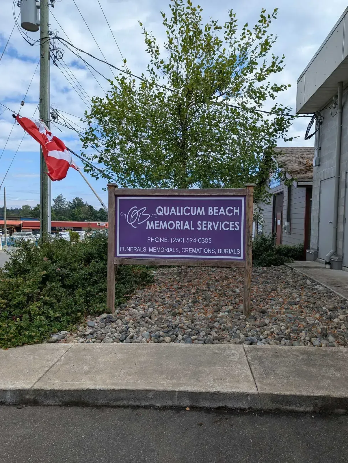Sign for Qualicum Beach Memorial Services on a cloudy day.
