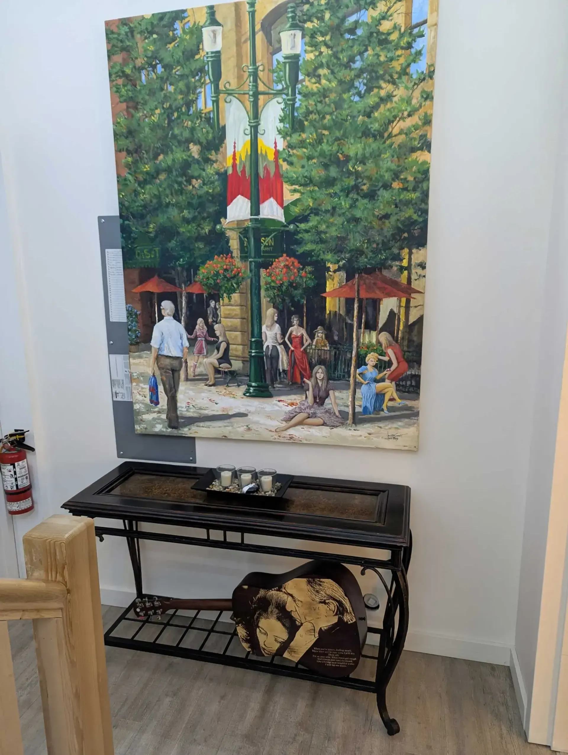 Painting of a European town square above a black wrought iron table with decorative items.