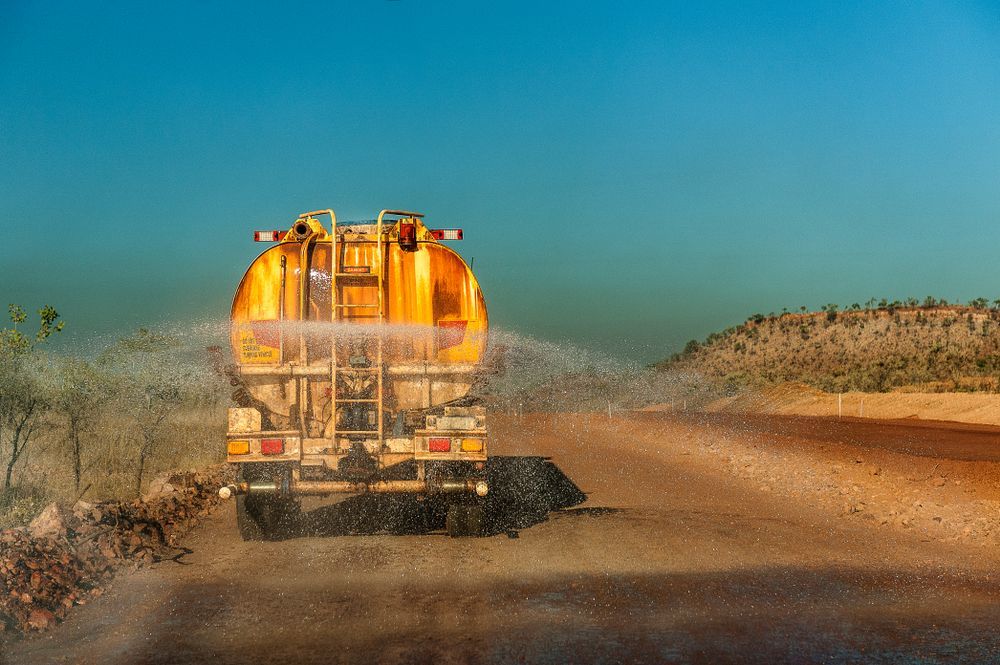 A Yellow Truck is Spraying Water on a Dirt Road — Sue's Clear Water in Seaforth, QLD 