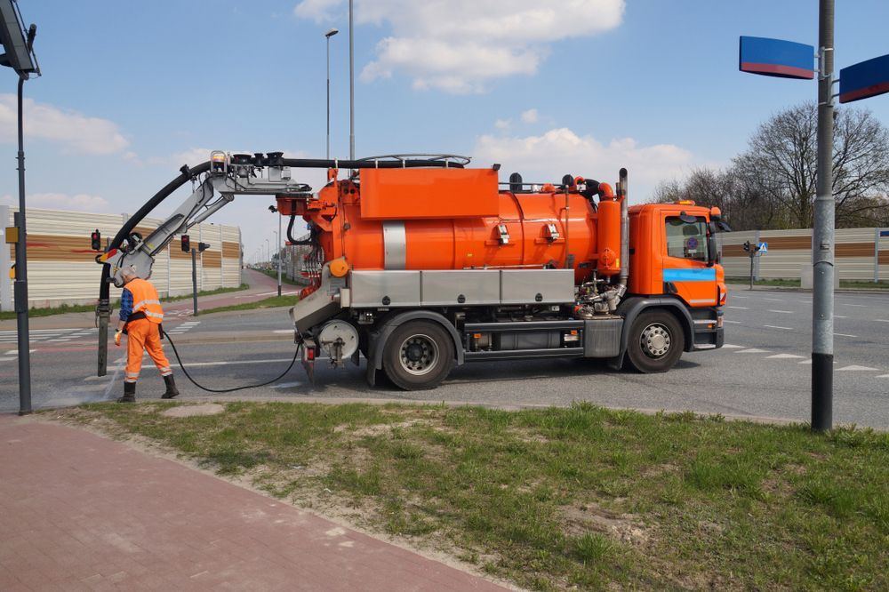 A Man is Standing Next to an Orange Vacuum Truck — Sue's Clear Water in Balnagowan, QLD 