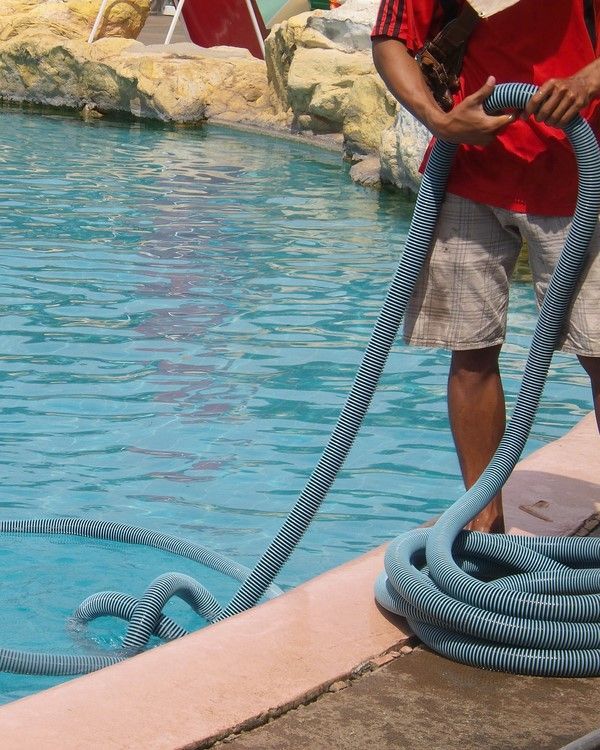 A Man in a Red Shirt is Holding a Hose Near a Pool — Sue's Clear Water in Marian, QLD 