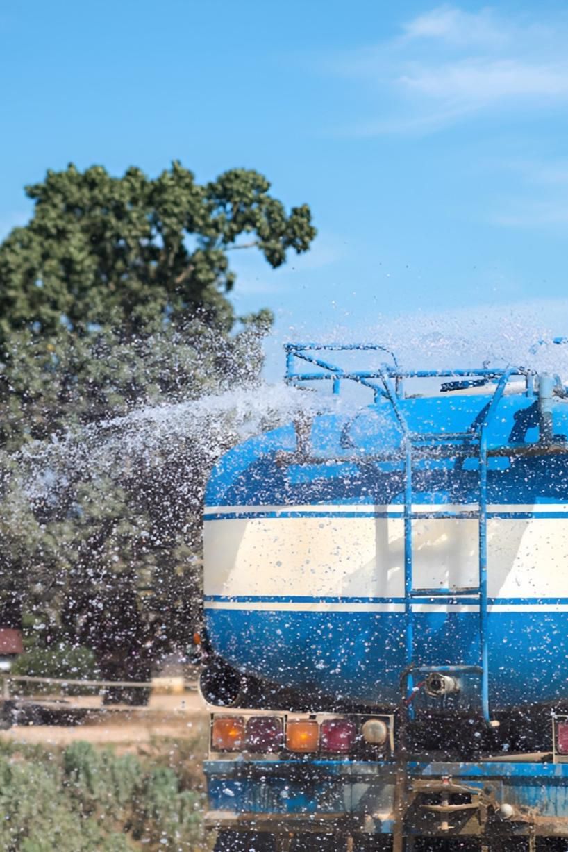 A Blue and White Water Truck is Spraying Water on Trees — Sue's Clear Water in Calen, QLD 