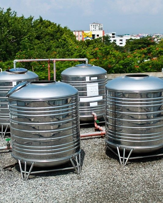 A Group of Stainless Steel Water Tanks Are Sitting on Top of a Gravel Roof — Sue's Clear Water in Balnagowan, QLD