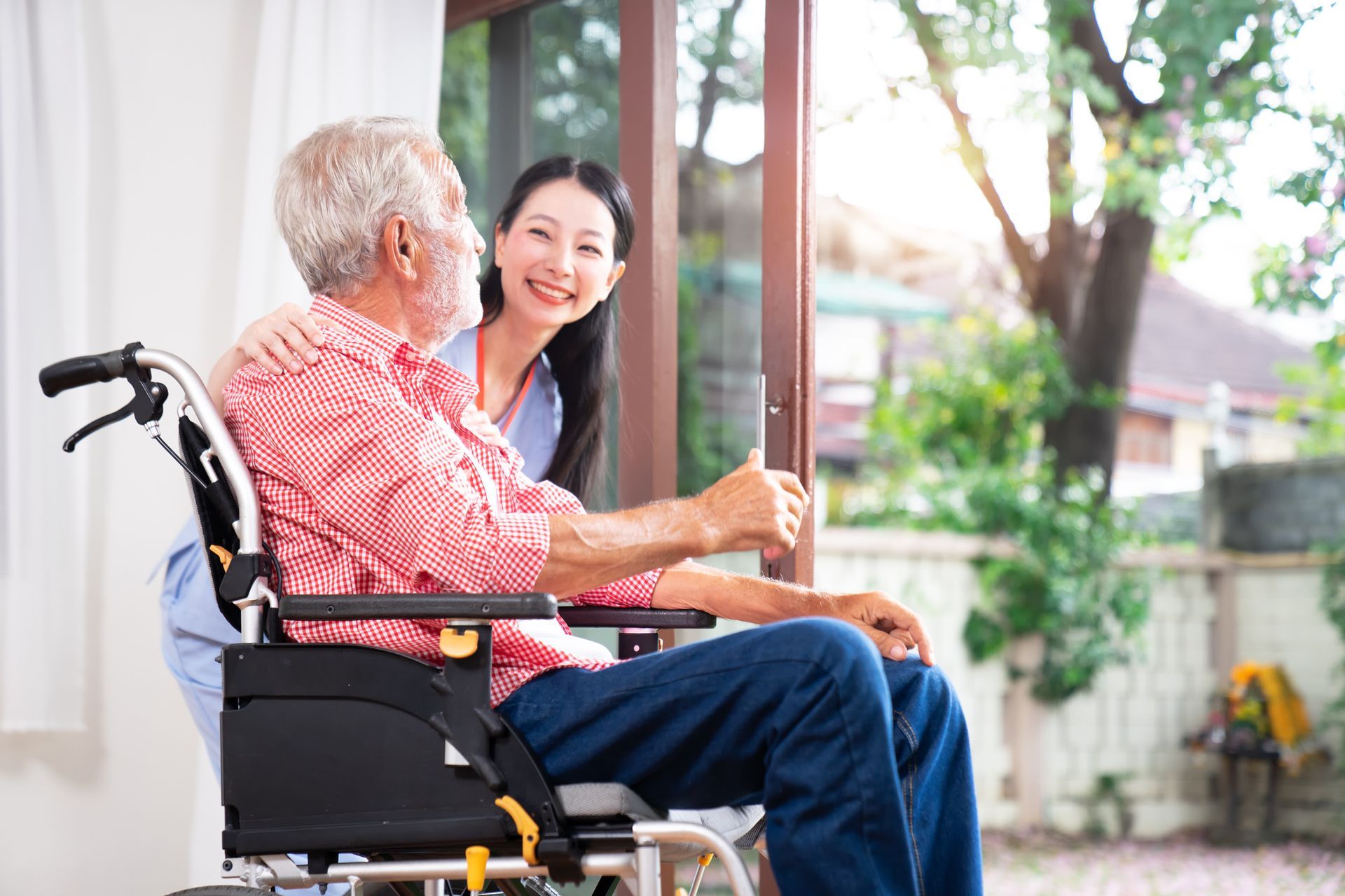 A woman is sitting next to an elderly man in a wheelchair.