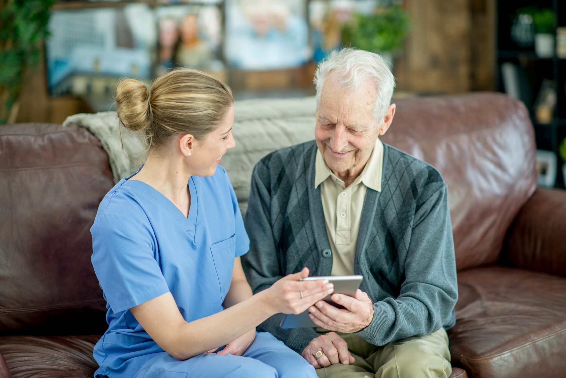 A nurse is showing an elderly man how to use a cell phone.