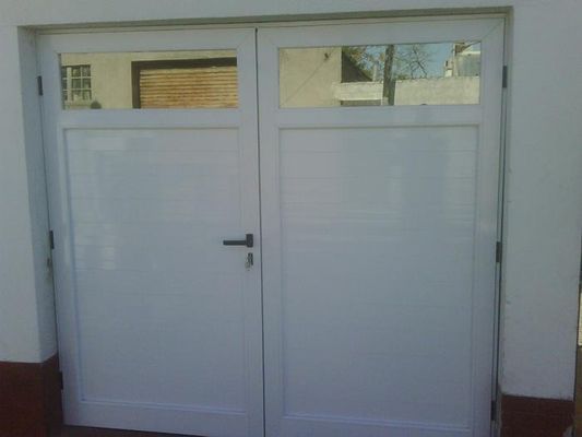 Puertas delanteras dobles blancas con ventanas estrechas y una manija central en la entrada del edificio.