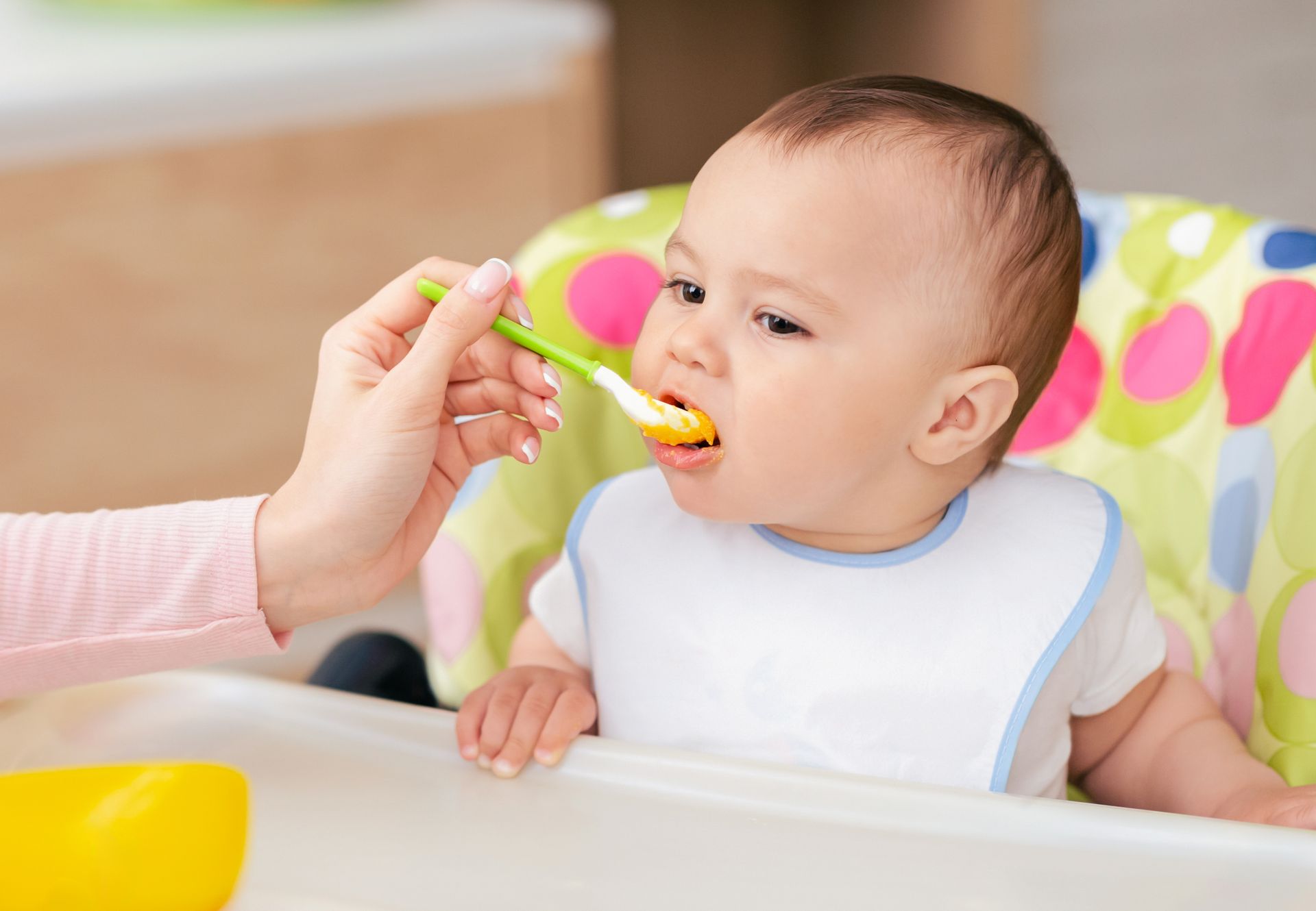 A picture of baby being spoon fed baby food. 