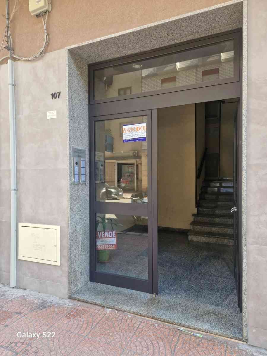 Ingresso dell'edificio con porta a vetri, scala interna a vista e numero 107 accanto alla porta.