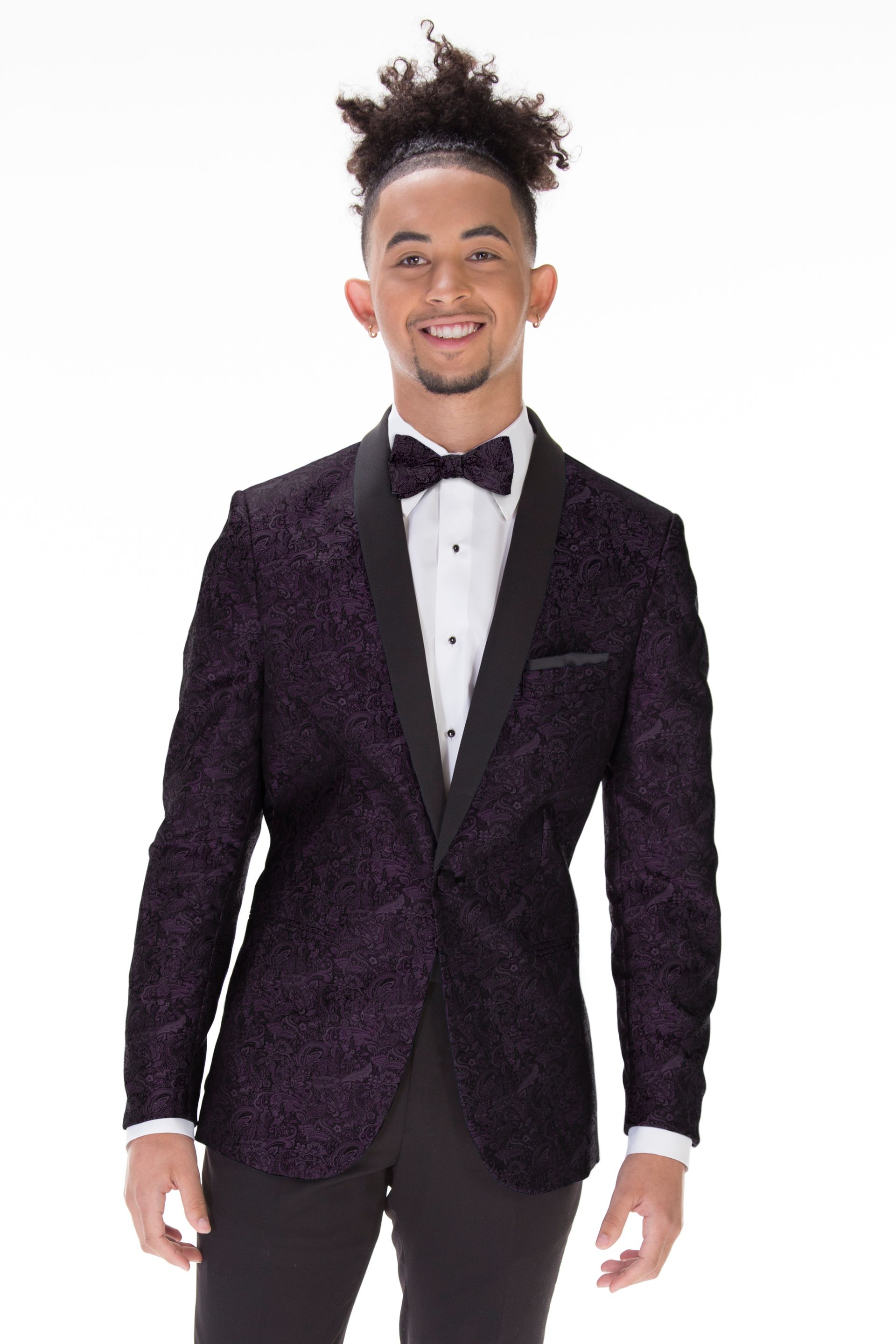 A man is wearing a purple tuxedo jacket and bow tie.