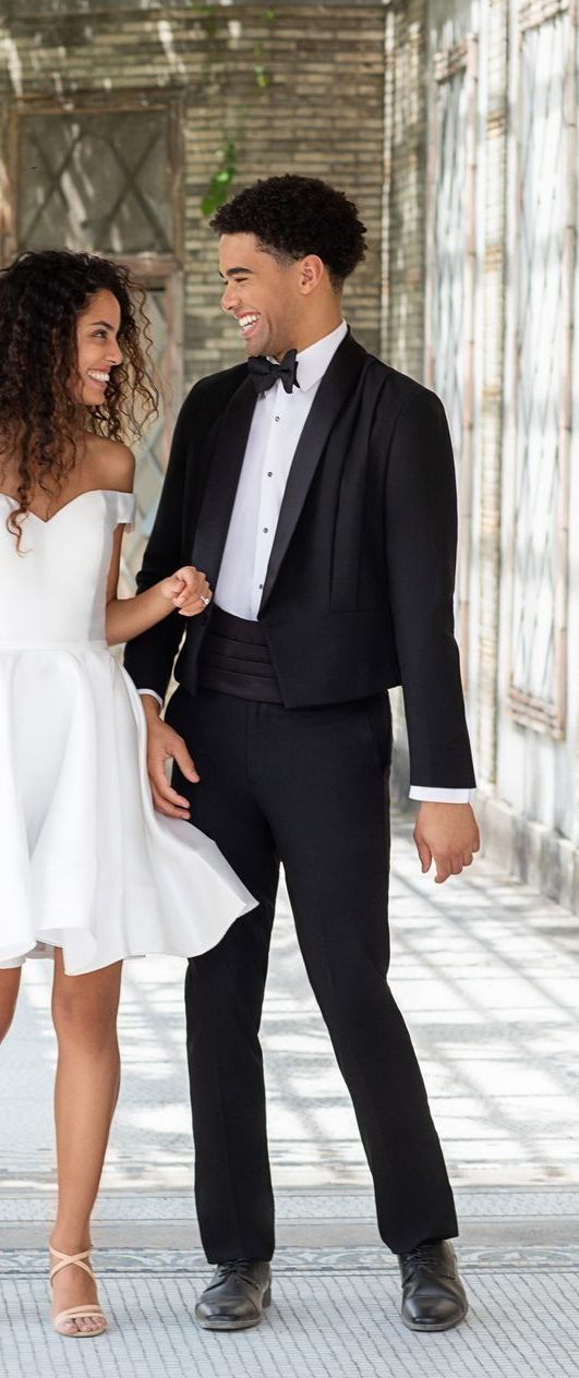 A man in a tuxedo and a woman in a white dress are standing next to each other.
