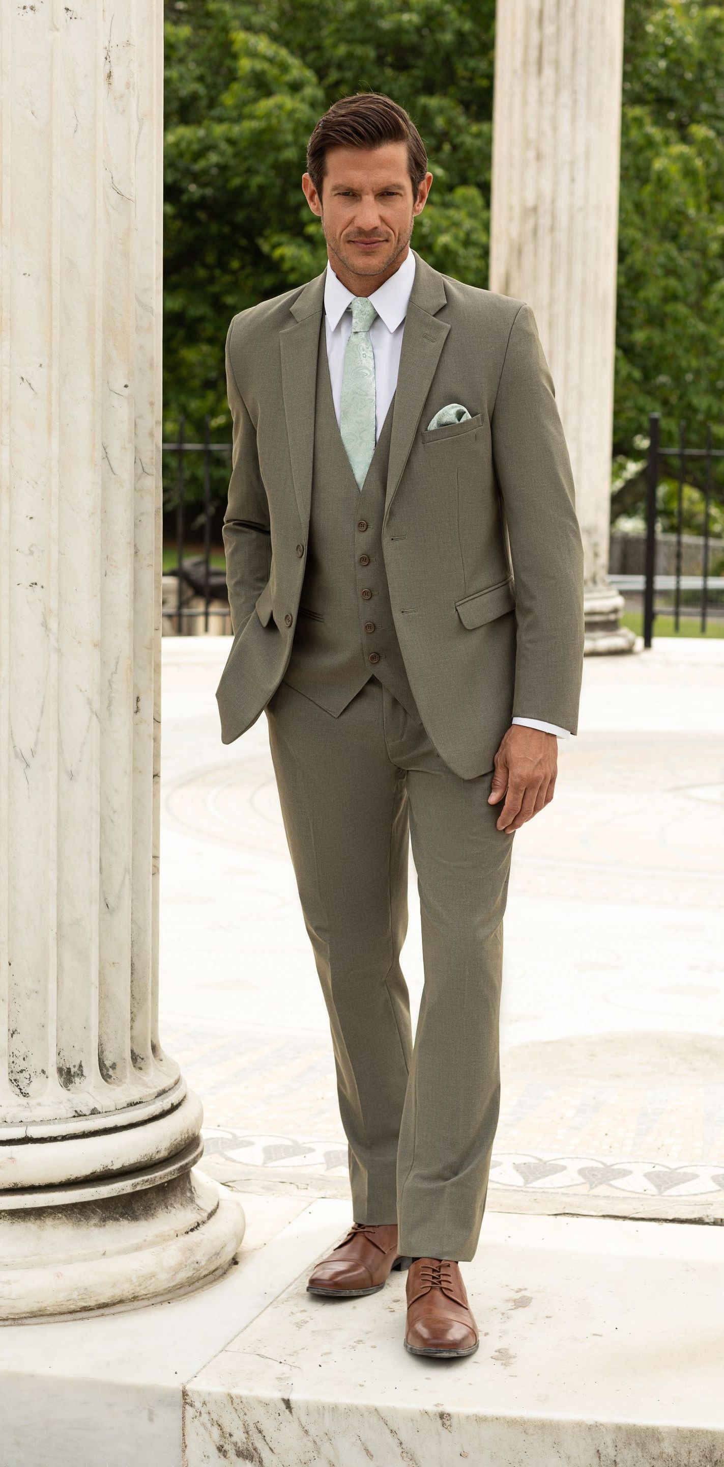 A man in a suit and tie is standing next to a column.