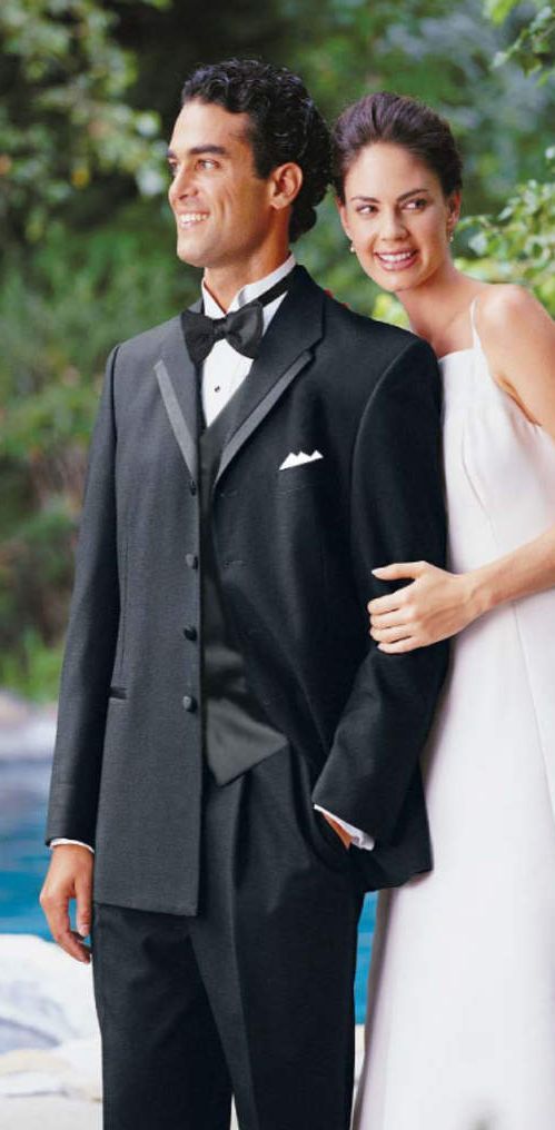 A man in a tuxedo is standing next to a woman in a white dress.