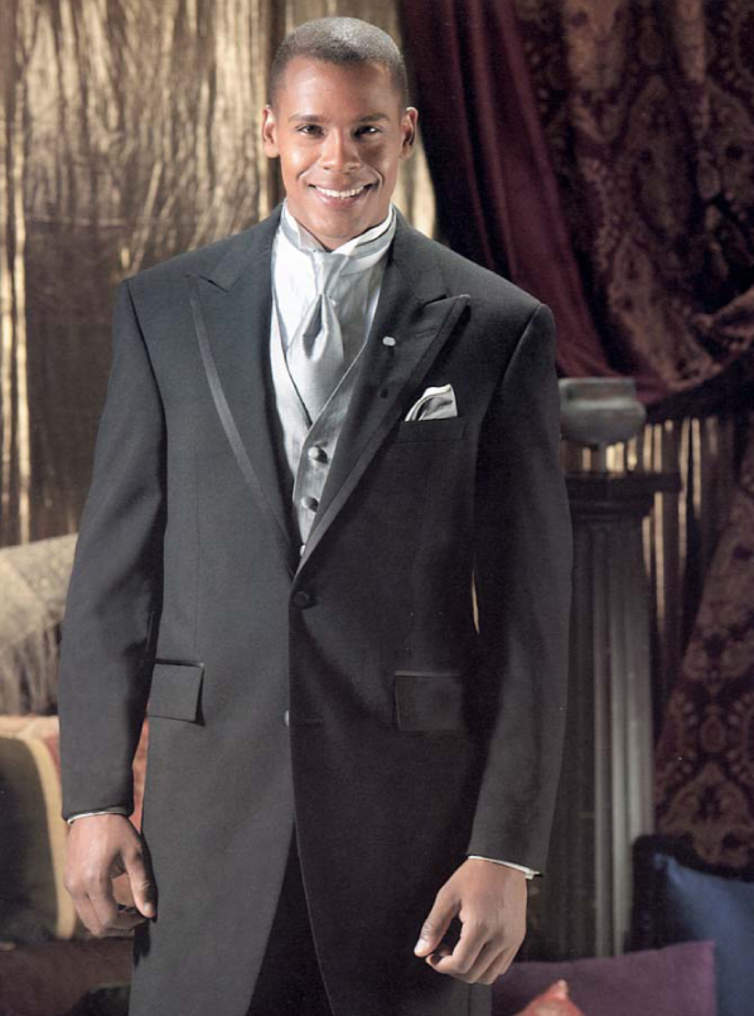 A man in a tuxedo is smiling in a room