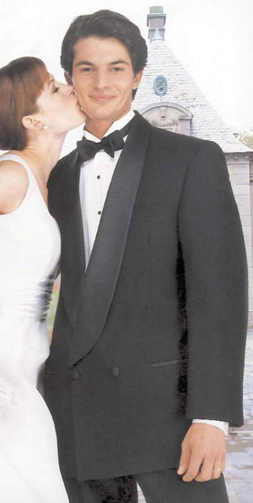 A woman is kissing a man in a tuxedo.