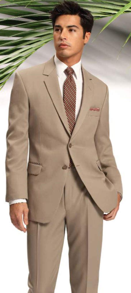 A man in a tan suit and tie is standing in front of a palm tree.