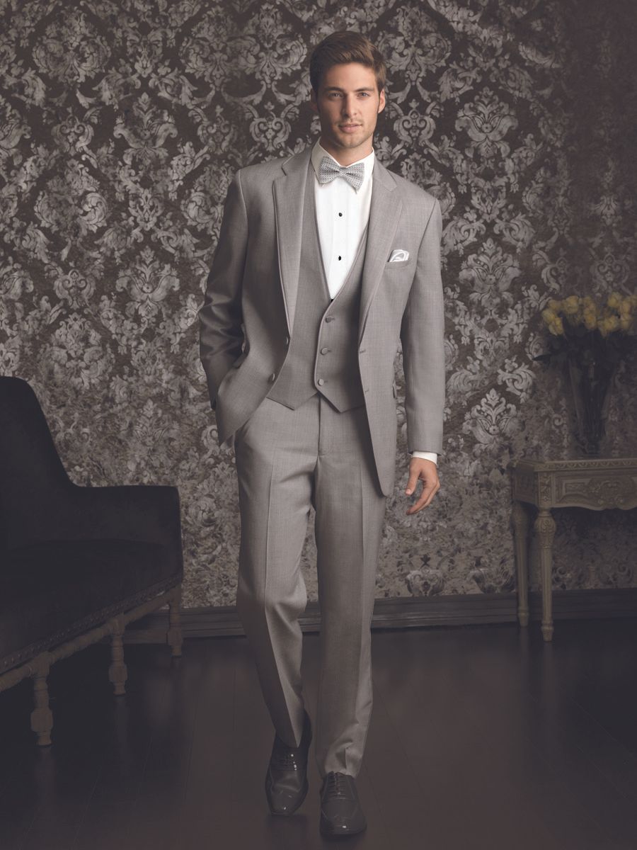 A man in a tuxedo and bow tie is standing in a room.