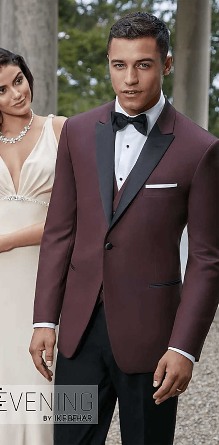A man in a burgundy tuxedo is standing next to a woman in a white dress.