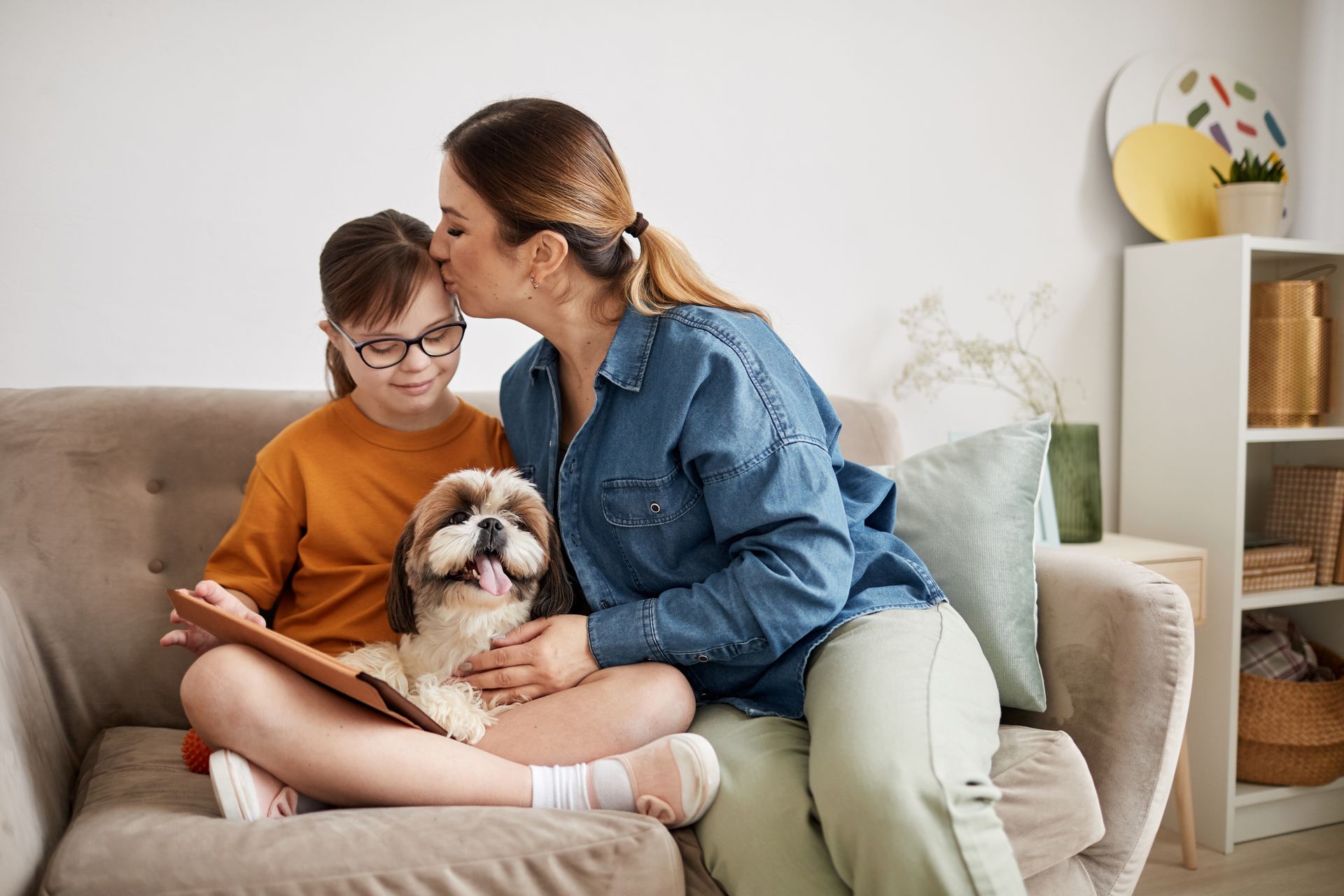 A woman and a child are sitting on a couch with a dog.