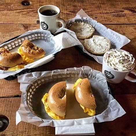 A wooden table topped with baskets of food and coffee cups.