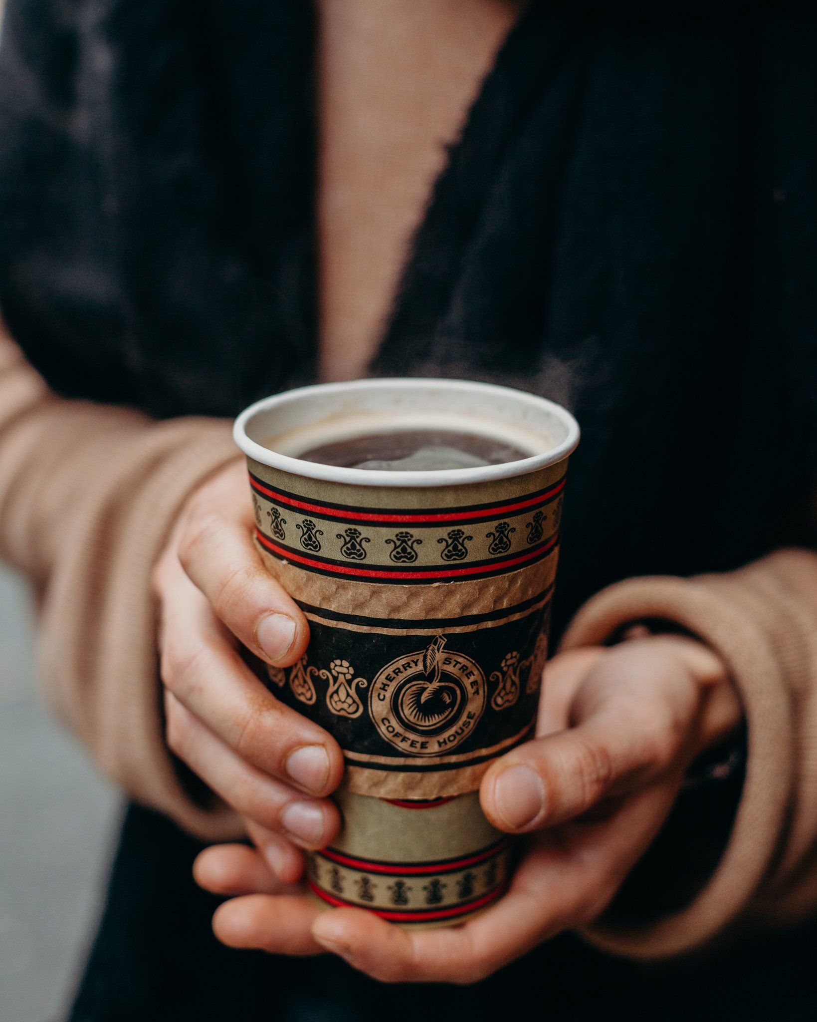 A person is holding a cup of coffee in their hands.