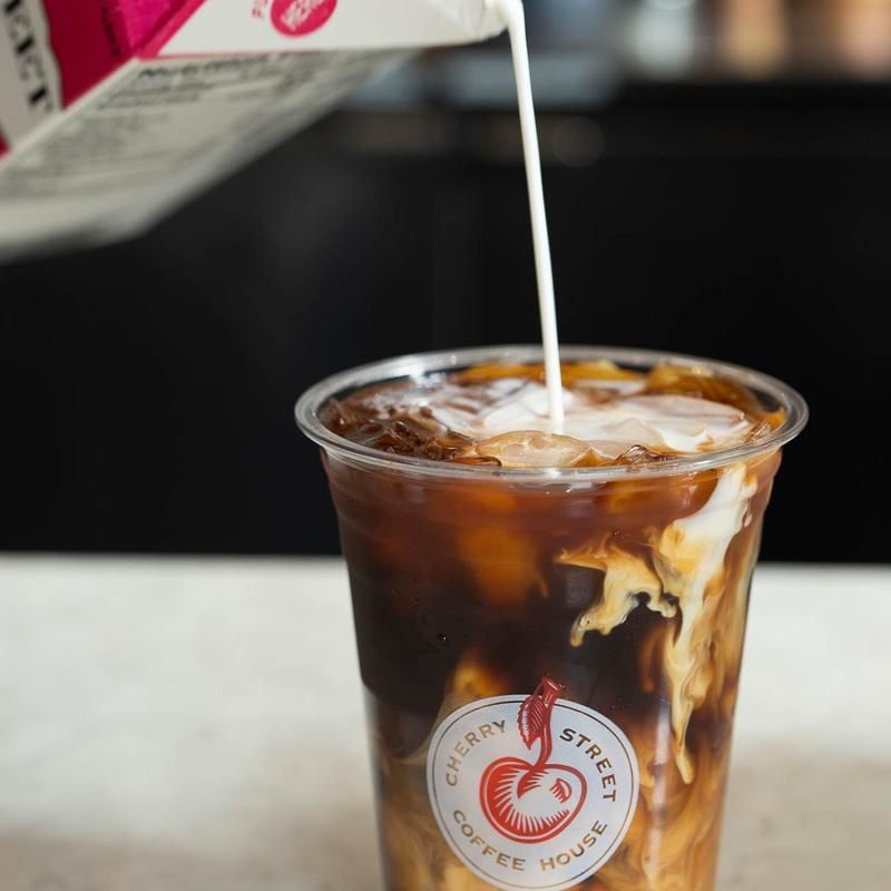 Milk is being poured into a cup that says cherry street coffee house
