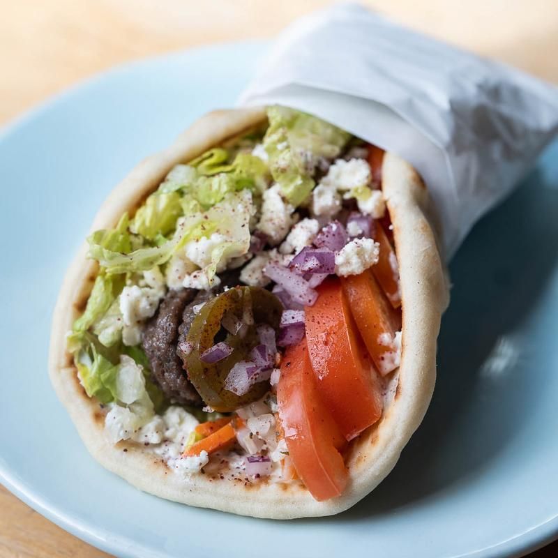 A close up of gyro sandwich on a blue plate.