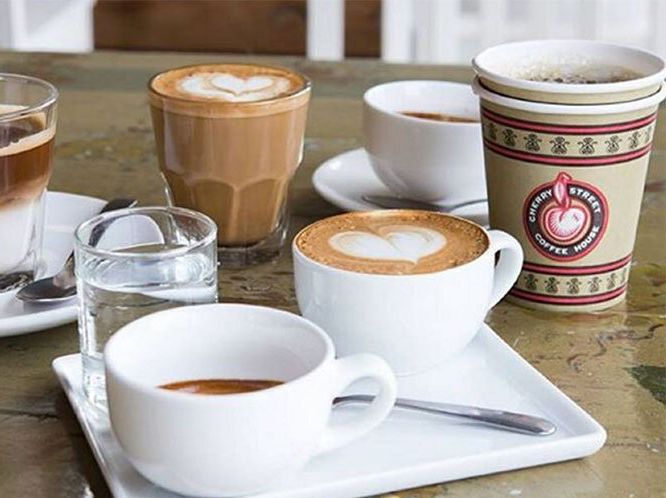 A table topped with cups of coffee and a glass of water