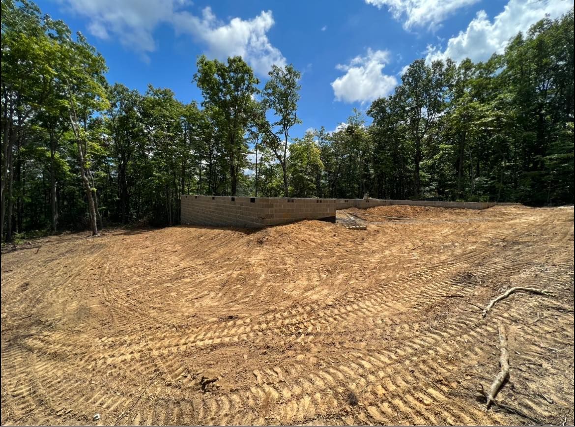 A dirt field with trees in the background and a blue sky