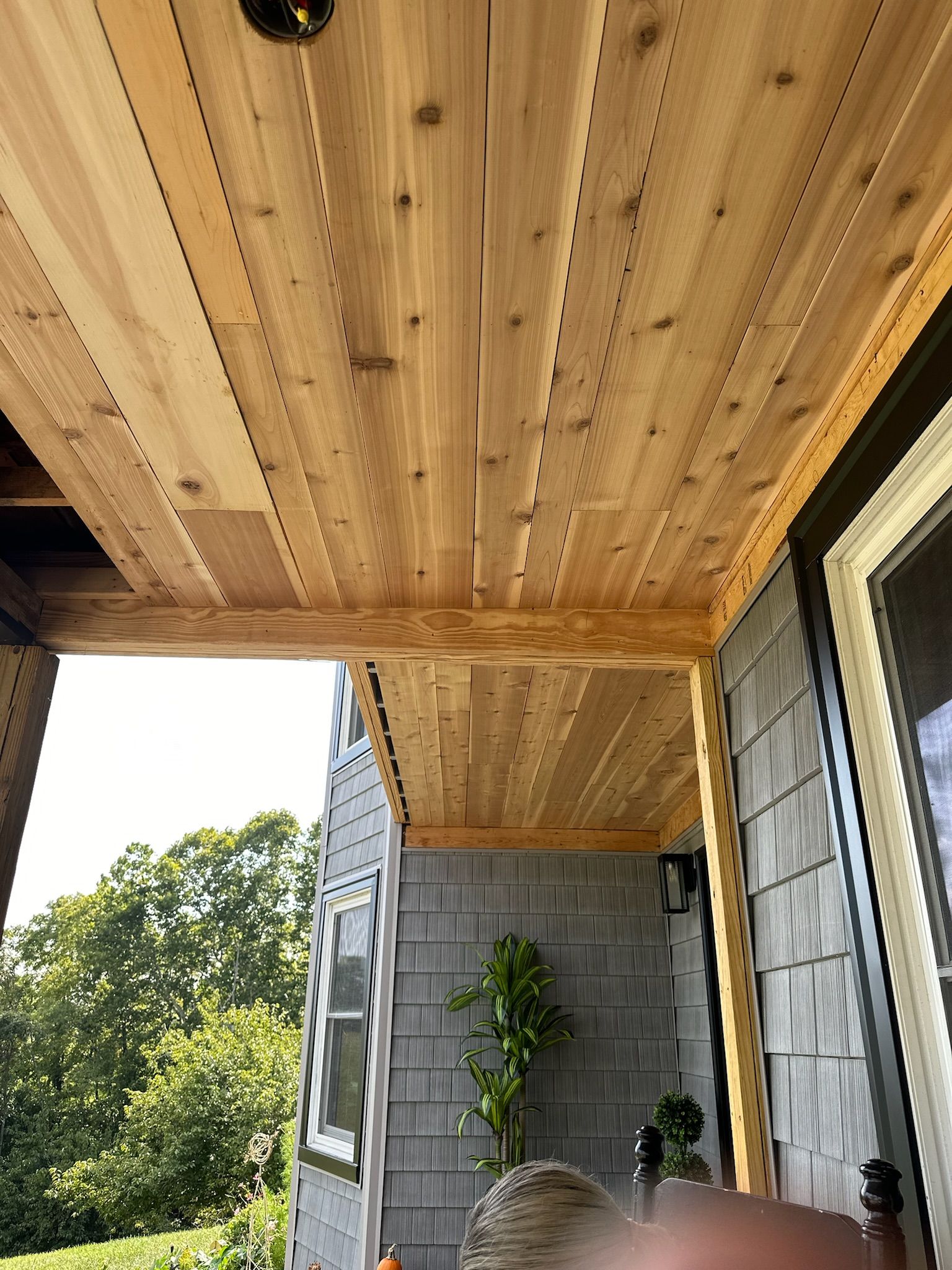 A person is sitting on a porch with a wooden ceiling.