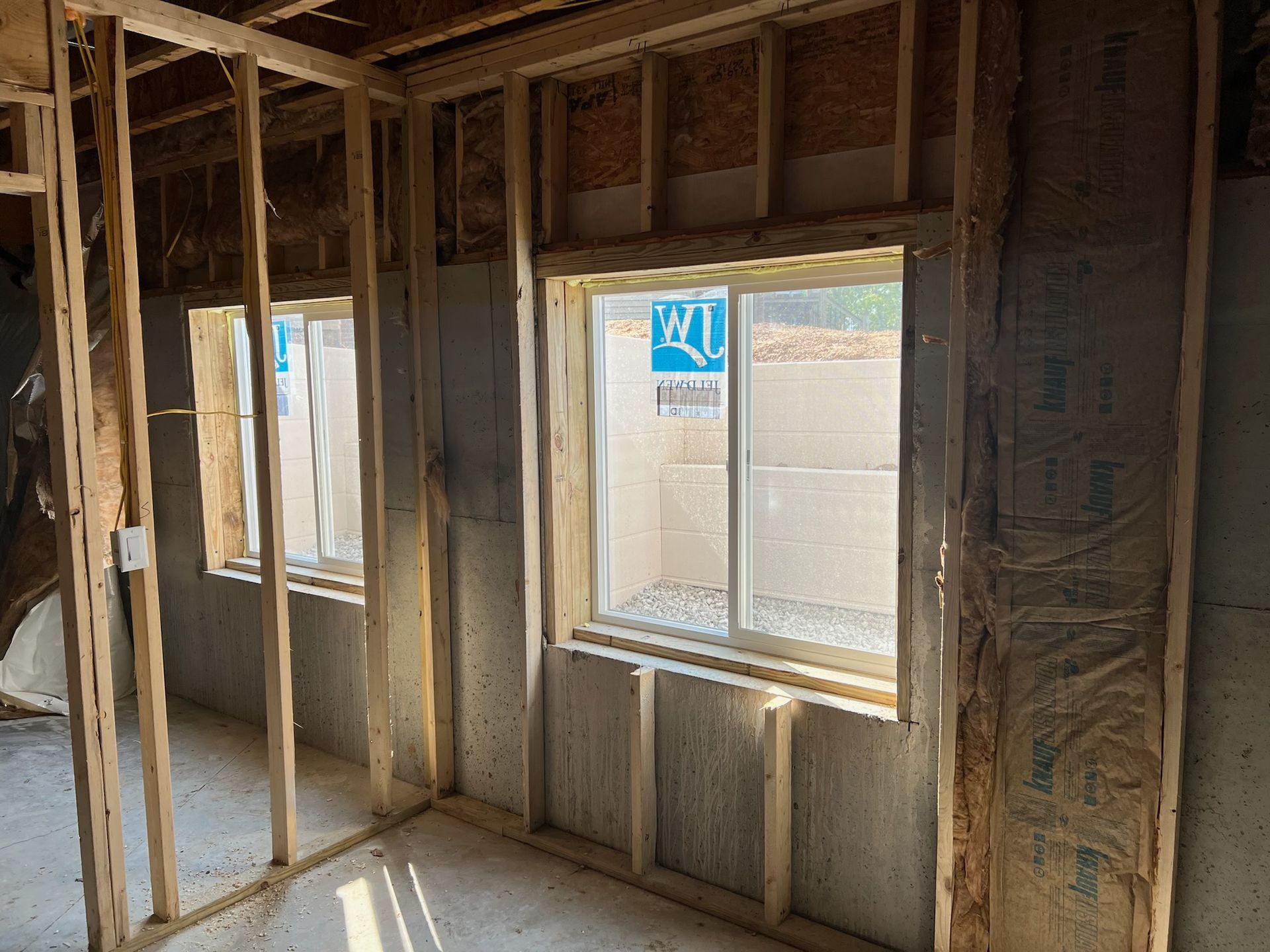 White window well with ladder, leading to window under brick wall, filled with gravel.
