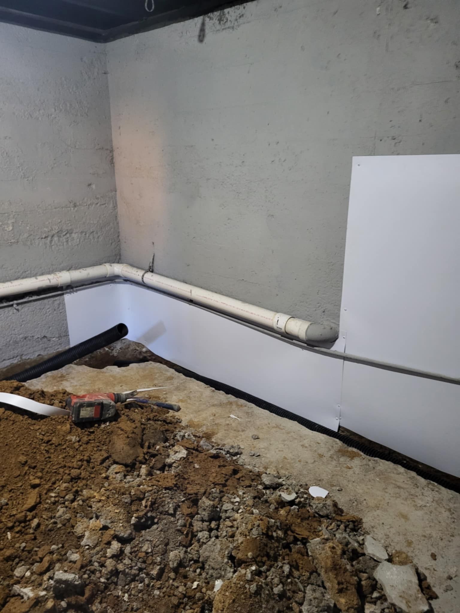 Basement with exposed drain pipes and freshly dug earth, ready for plumbing or construction.