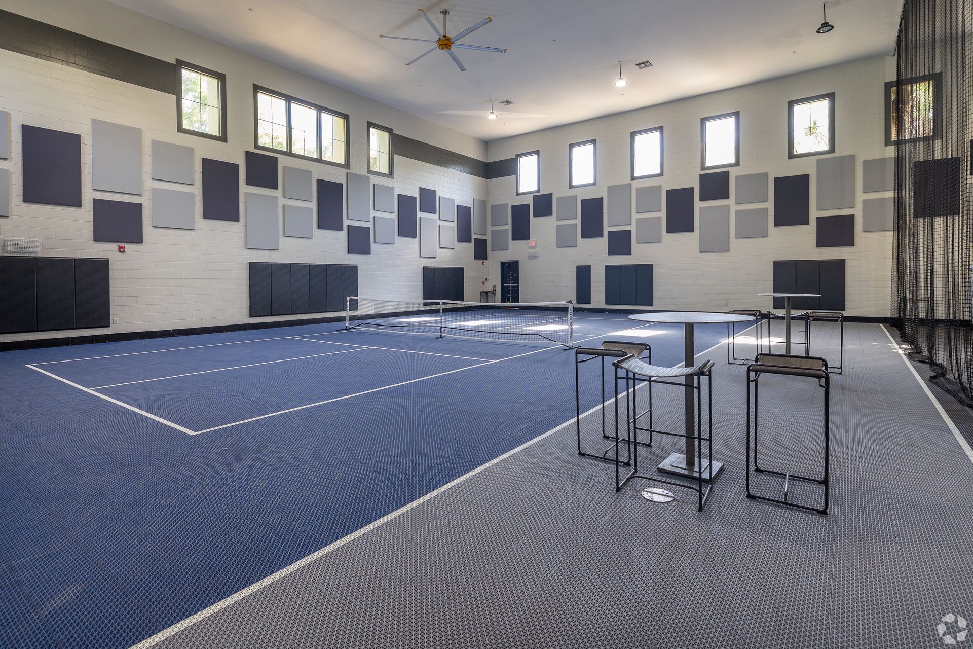Blue and gray carpeted room with soundproofing panels on walls; tables and chairs set up.
