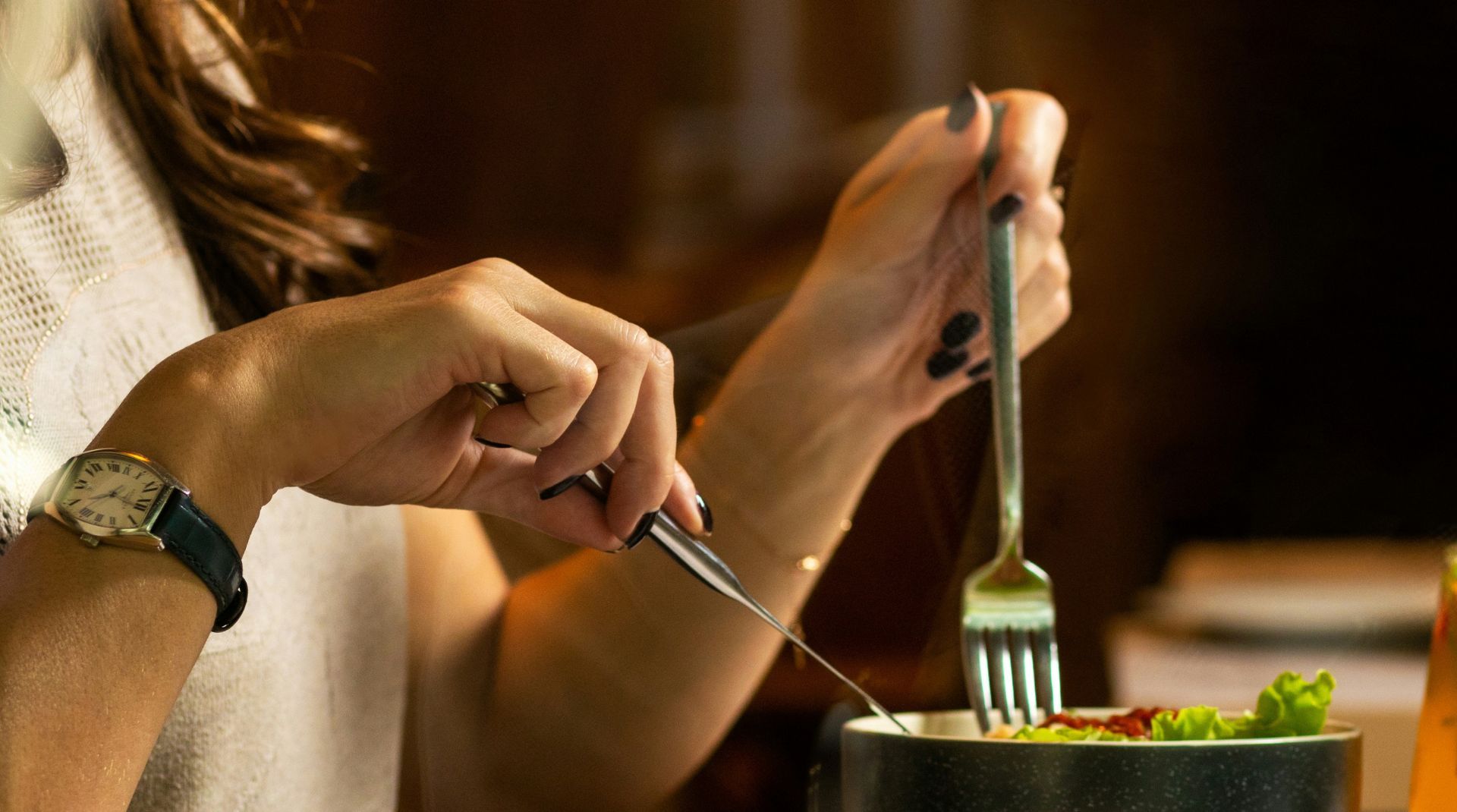 A woman enjoying a fresh salad with a fork and knife, highlighting mindful eating and the importance