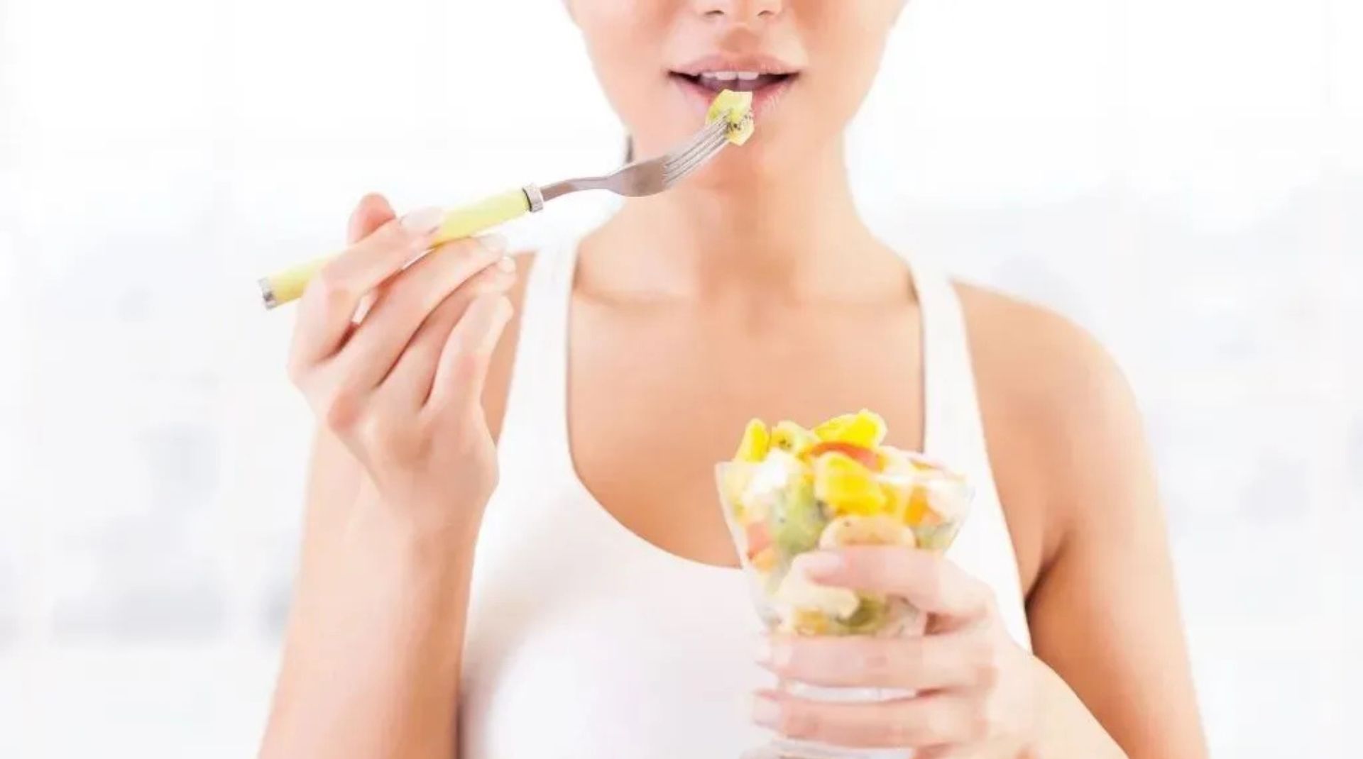 A woman enjoying a fresh fruit salad, highlighting the connection between nutrition and oral health