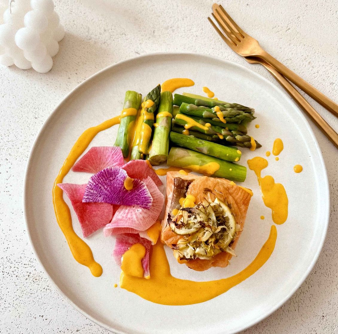 A plate of food with asparagus and a flower on it