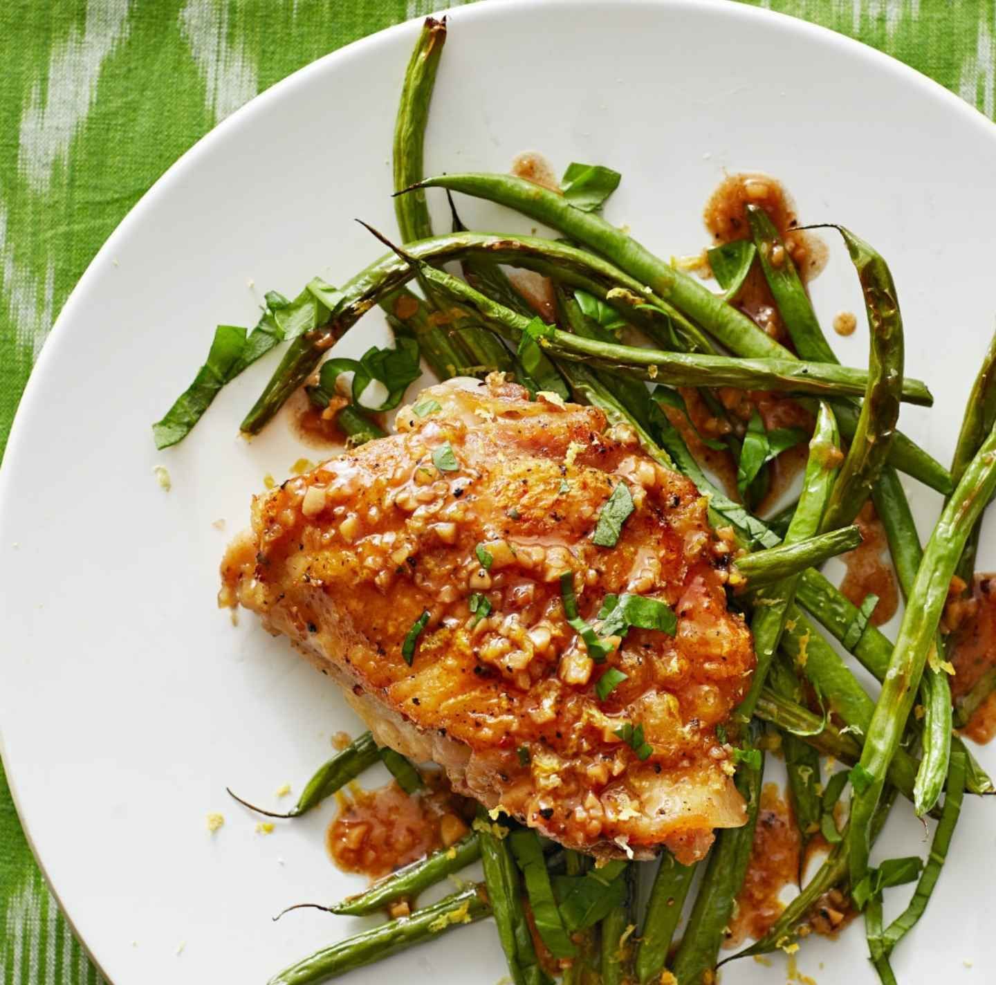 A white plate topped with green beans and chicken