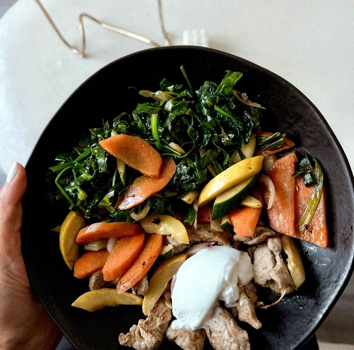 Paleo dinner by Tricia Williams for Daily Dose featuring sautéed leafy greens, roasted carrots, zucchini, and pasture-raised chicken topped with a dairy-free yogurt sauce. A nutrient-dense, whole-food meal designed for optimal health and longevity.