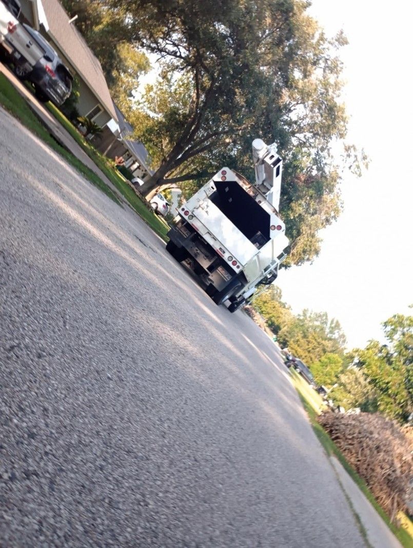 A white garbage truck is parked on the side of the road