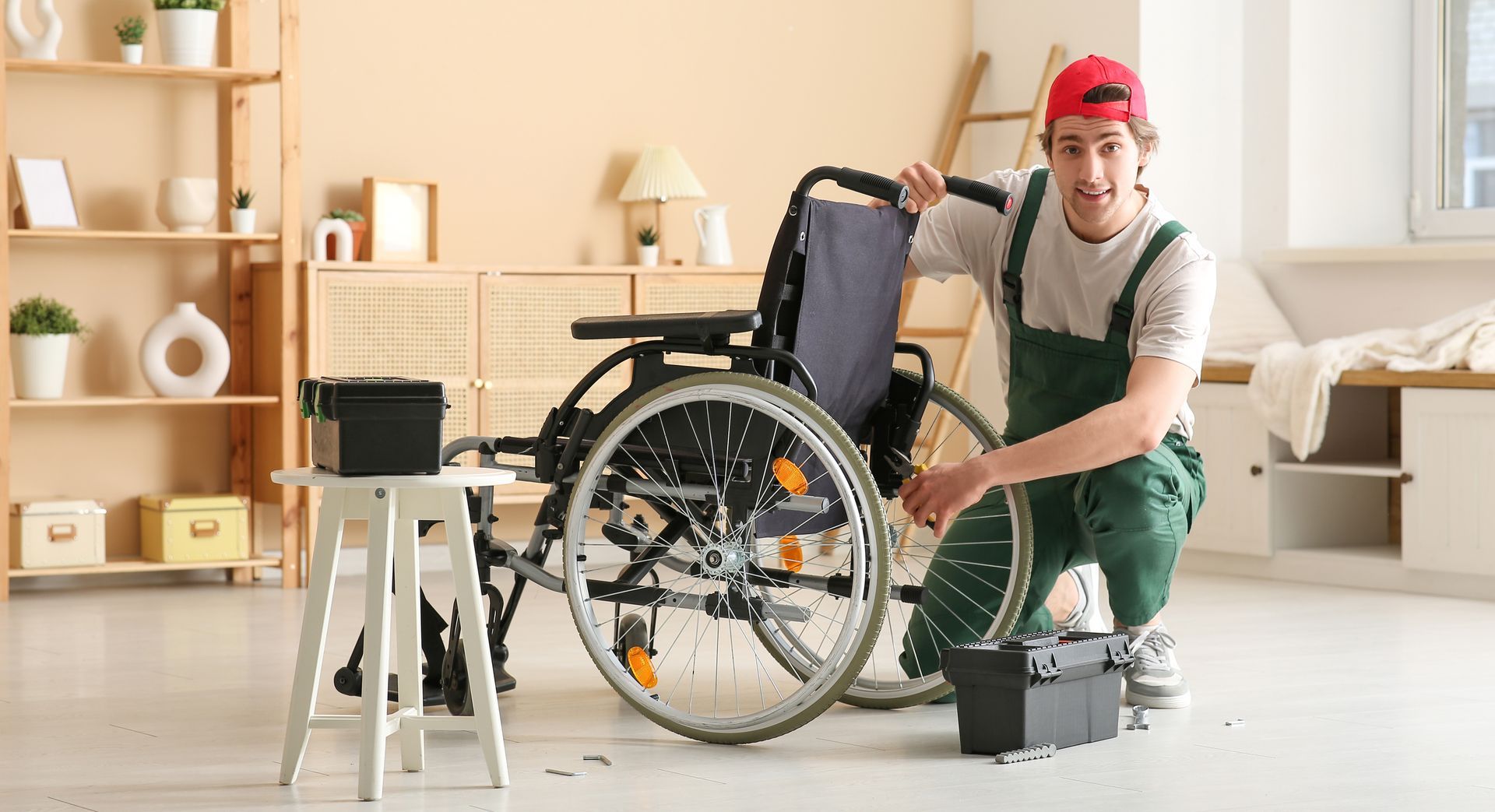 Person repairing a wheelchair in a bright room, with tools and a black toolbox nearby. Person repairing a wheelchair in a bright room, with tools and a black toolbox nearby.